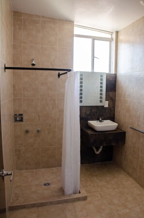 Una ducha con puerta de vidrio, un lavabo blanco y un espejo sobre él.