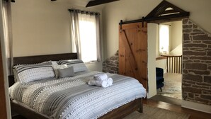 Un dormitorio con una cama de madera, pared de piedra y viga de techo de madera.