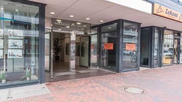 A building entrance with glass doors, a sign for 'Haus am Meer,' and a 'Leksus' sign above.