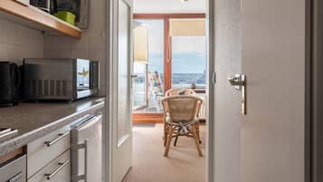 A kitchen with a microwave, a coffee maker, and a wicker chair in a room with a view.