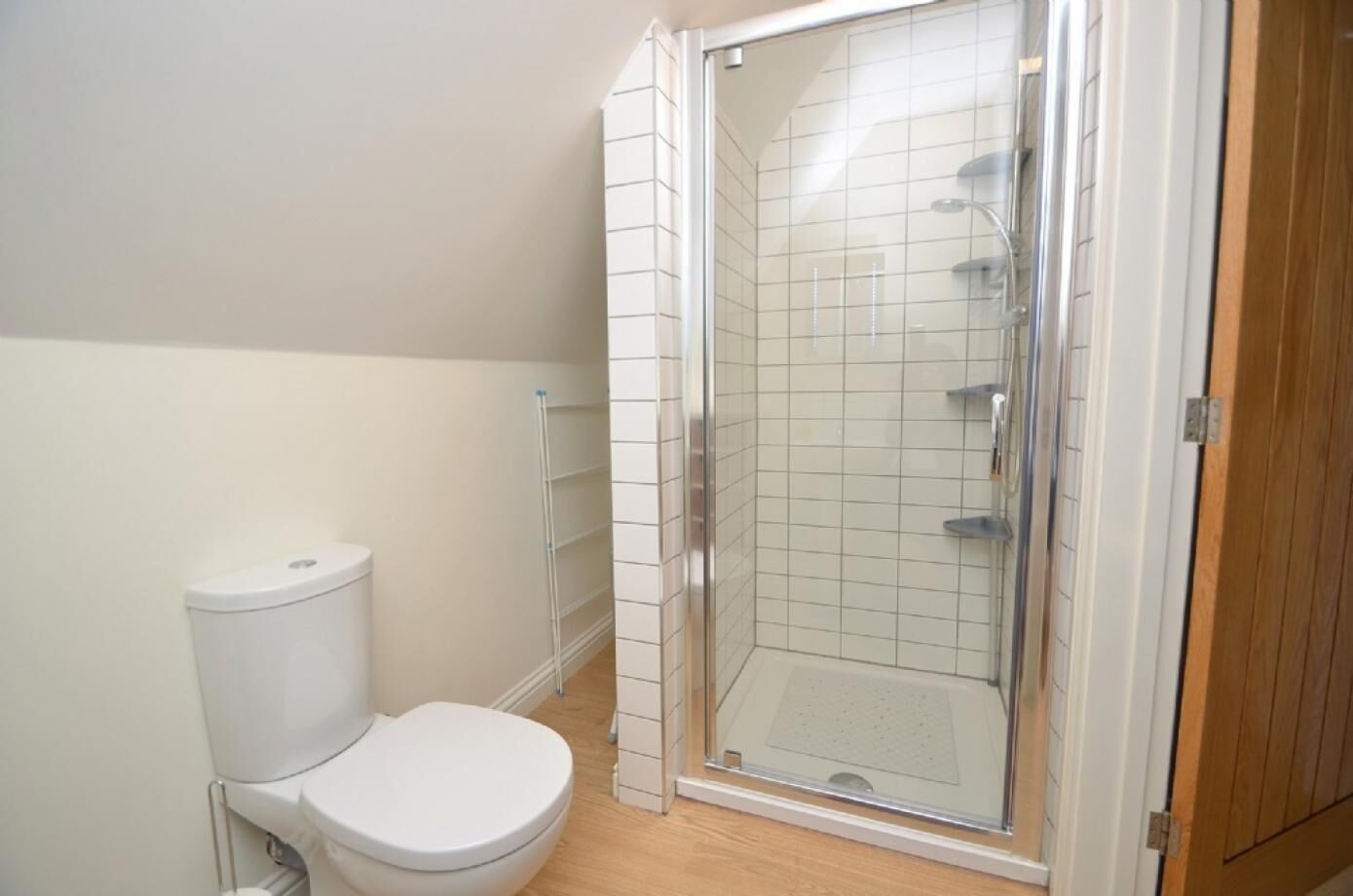 Une salle de bain comprenant des toilettes, un espace douche et un meuble en bois.