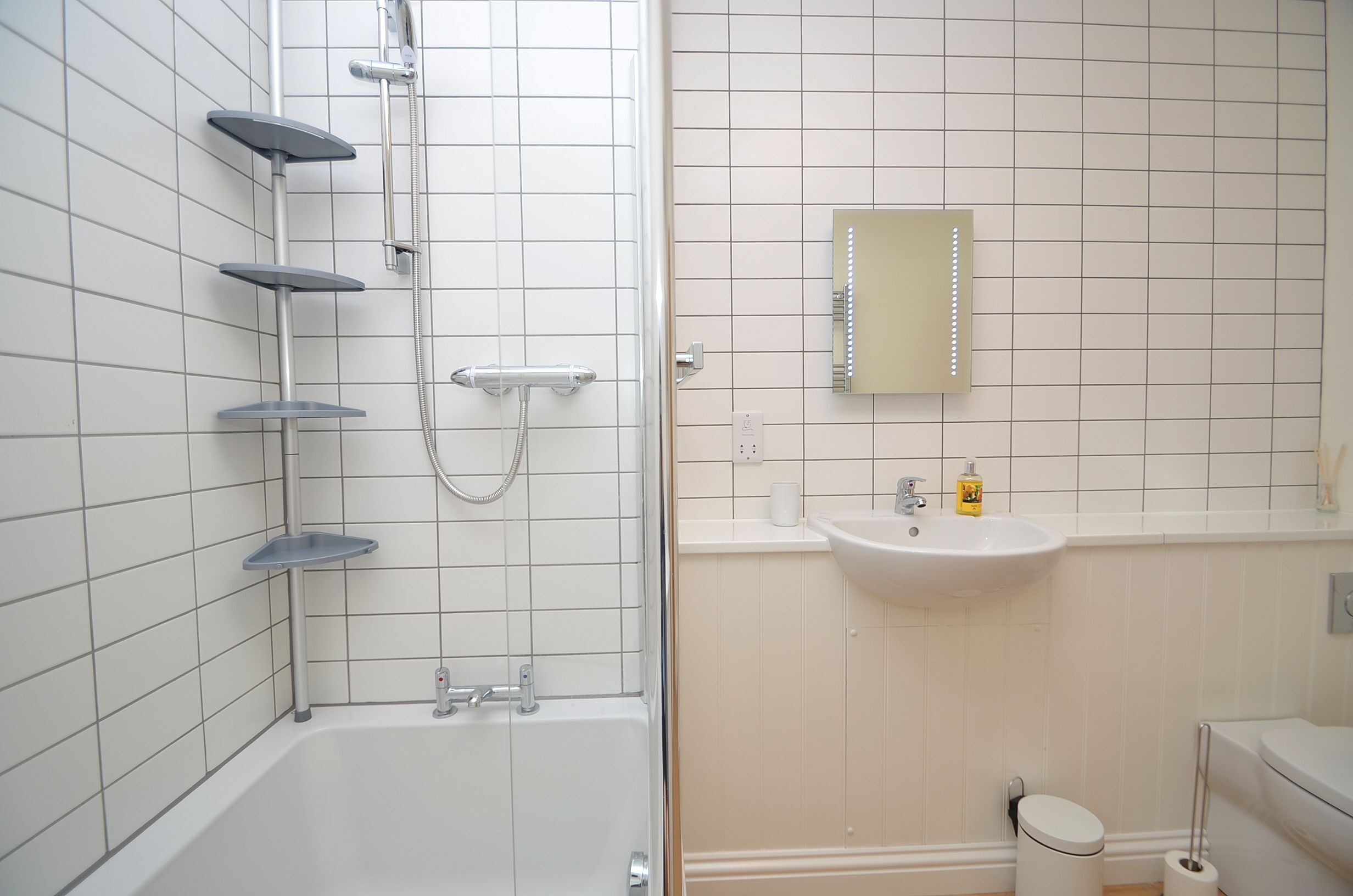 A bathroom with a bathtub, a shower, a sink, and a mirror.