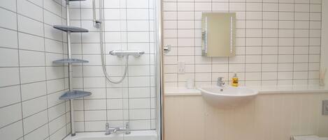 A bathroom with a bathtub, a shower, a sink, and a mirror.