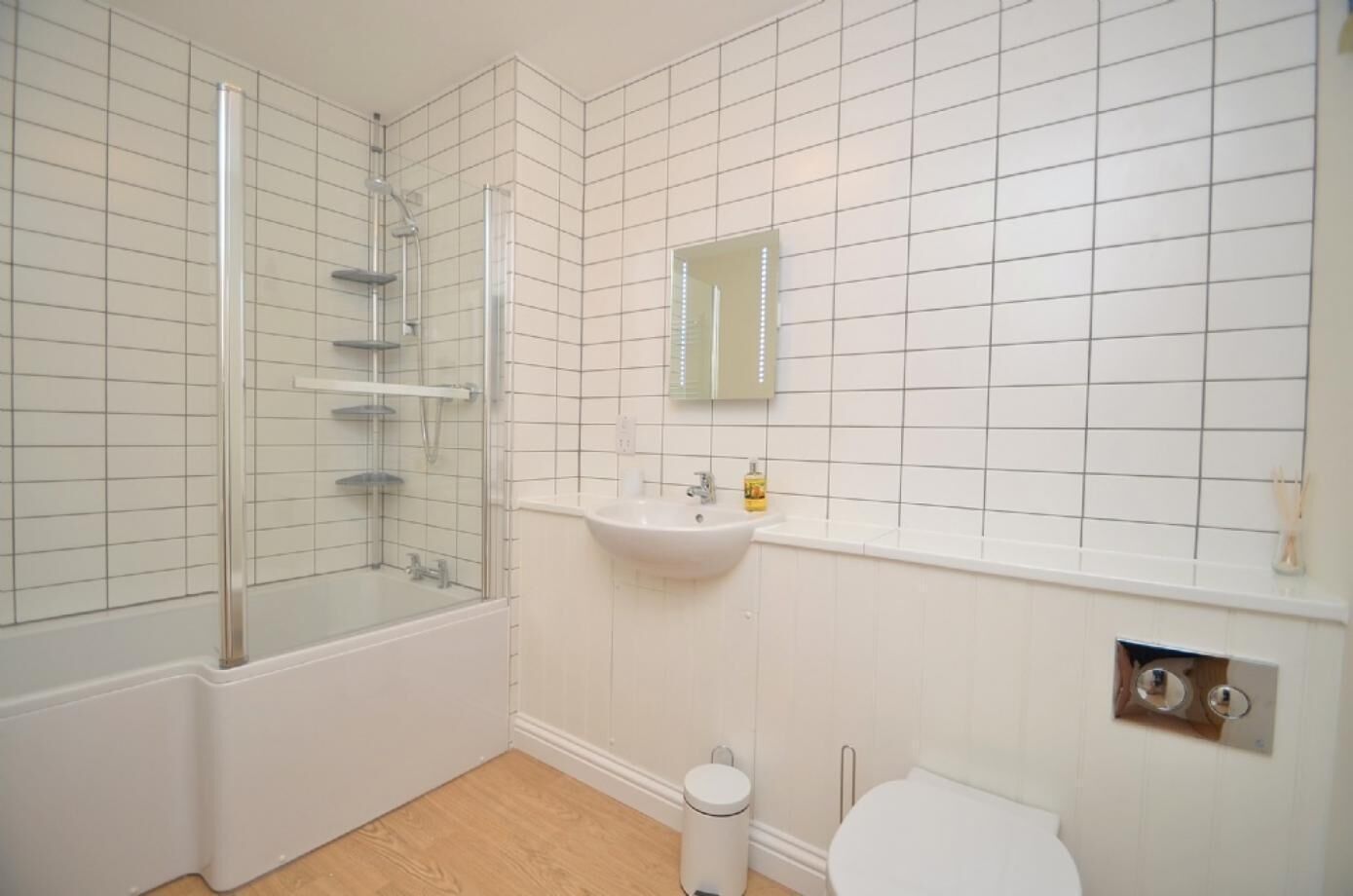 A bathroom with a glass-enclosed shower, a white sink, and a toilet.