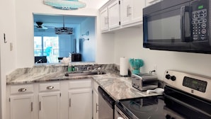 A modern kitchen with white cabinets, a black microwave, a toaster, and a dishwasher. - Ocean view 2 bedroom, 2.5 bath townhouse. Nicely upgraded! (St. Augustine)