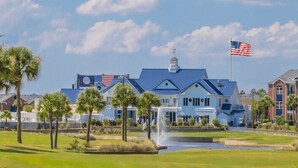 Ein großes Gebäude mit blauem Dach und einer amerikanischen Flagge, umgeben von Palmen und einem Golfplatz.