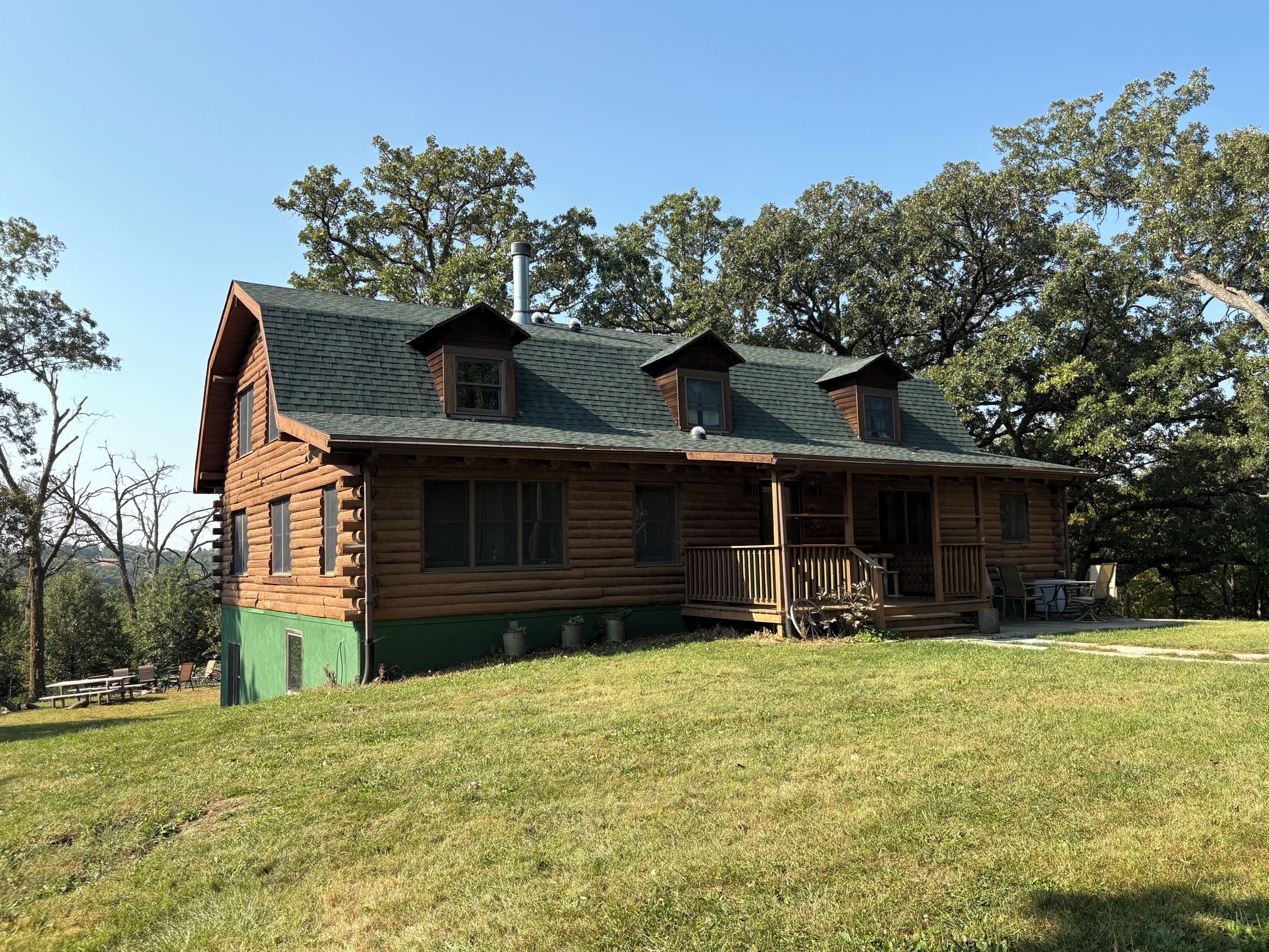 A log cabin with a porch, multiple windows, and a chimney.