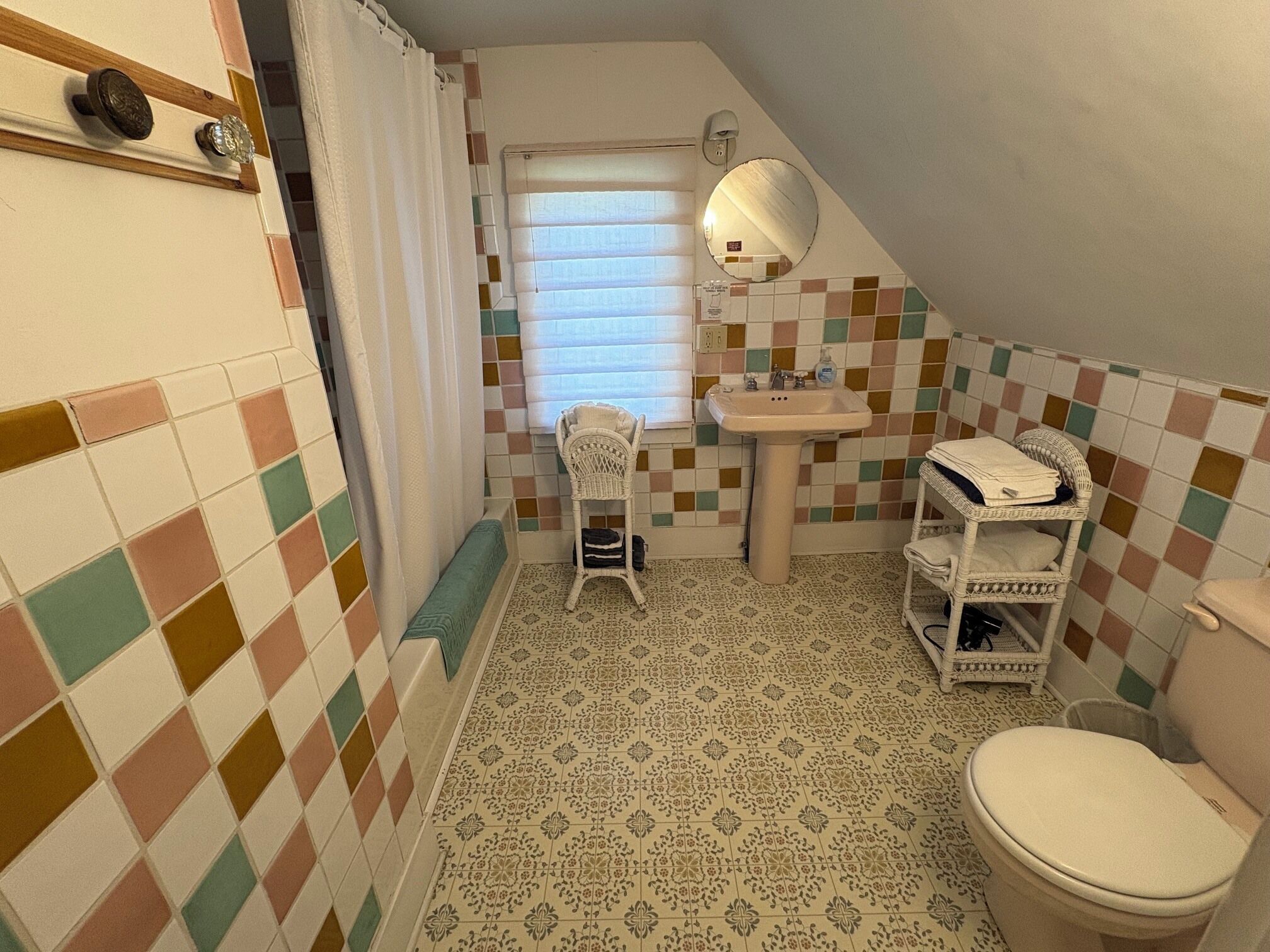 Une petite salle de bain carrelée, équipée de toilettes, d’un lavabo et d’une chaise.