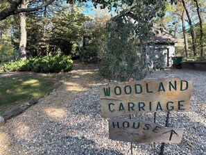 A wooden sign indicating the direction to the Woodland Carriage House. - Whiterock Conservancy (Coon Rapids)