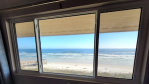 Ein Fenster mit Blick auf einen Strand und das Meer.