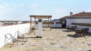 Eine Dachterrasse mit Steinböden, einer Pergola und Sitzgelegenheiten im Freien.