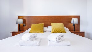 Ein ordentlich bezogenes Bett mit zwei Kissen, einem hölzernen Kopfteil und zwei Nachttischen mit Lampen.