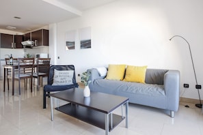 A modern living room with a sofa, coffee table, and dining area.