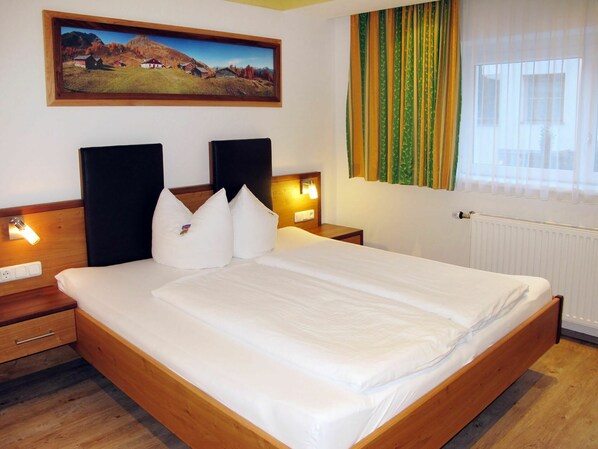 A hotel room with a wooden bed, two bedside tables, a nightstand, a painting of a landscape, and a window with curtains. - Stunning private villa for 20 people with WIFI, TV and terrace (Niederhof)