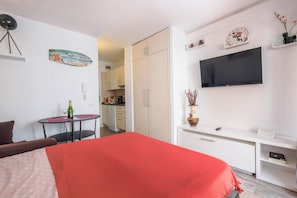 Une chambre d’hôtel équipée d’un lit, d’une télévision, d’un petit coin cuisine et d’une table à manger.