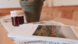 A table with a potted plant, a jar of jam, and a booklet. - Apartment "Toni - Obermösslhof" with Wi-Fi, Terrace & Mountain View (Lana)