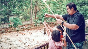 Um homem segurando uma vara de pesca, com uma criança e um menino observando.