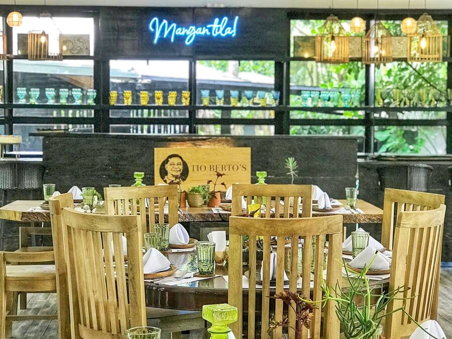 A restaurant with wooden tables and chairs, green glassware, and a neon sign reading "Margaritaville".