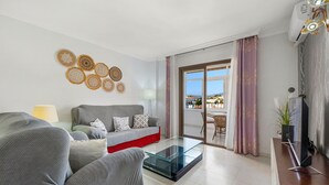 A modern living room with a sofa, a glass coffee table, and a TV on a wooden stand. - Beautiful Adriana Apartment with Pool, Air Conditioning, Wi-Fi, Balcony, Terrace, Stunning Views (Fuengirola)