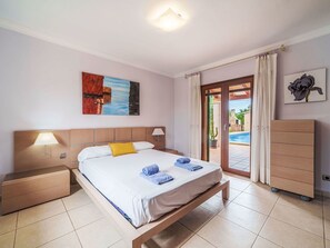 A hotel room with a bed, bedside lamps, a painting, a view of the pool, and a wardrobe. - Beautiful private villa for 6 people with A/C, private pool, WIFI, TV and terrace (Manacor)