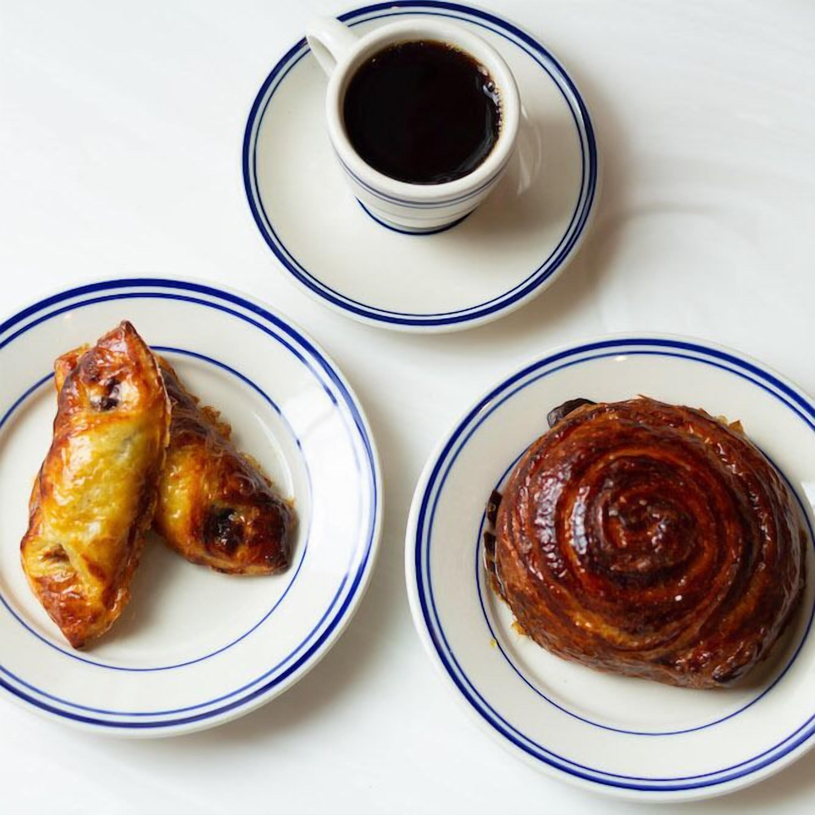 A plate with two pastries and a cup of coffee on a white table.