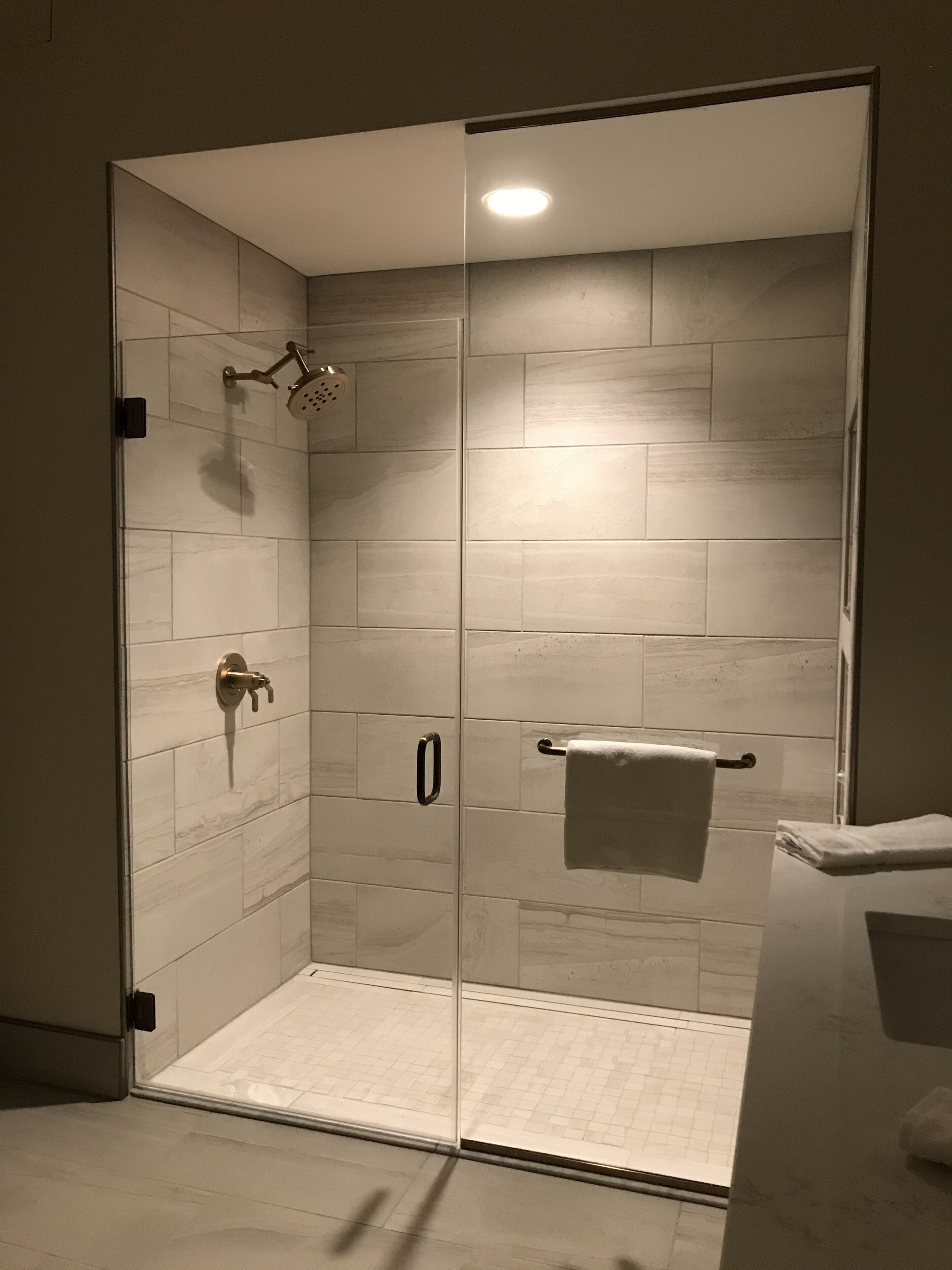 Um chuveiro de canto com porta de vidro, um porta-toalhas e um chuveiro.