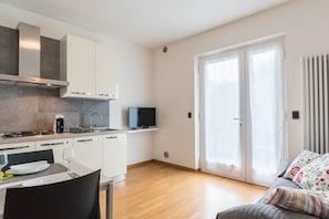 A modern kitchen with white cabinets, a gas stove, and a built-in TV. - Holiday Apartment “Casa Stefi N2” close to lake Garda with Wi-Fi, Balcony, Garden & Pool (malcesine)