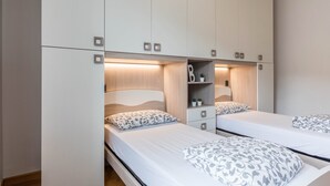 Une chambre avec deux lits, une armoire et une étagère.