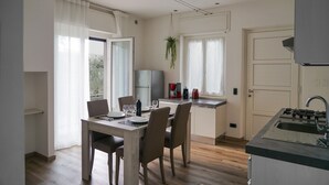 Une cuisine moderne avec un coin repas, une cuisinière encastrée et une plante suspendue.