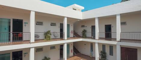 A multi-story building with a central courtyard featuring a swimming pool, balconies, and outdoor seating.
