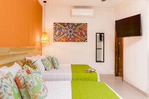 Habitación de hotel con dos camas, un cuadro de pared colorido, un televisor de pantalla plana y una puerta de madera.