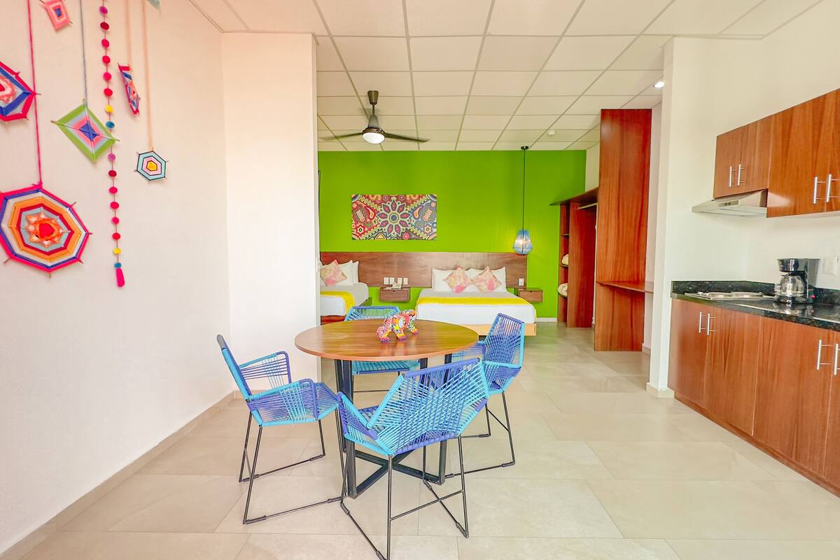 A hotel room with a dining area, a kitchen, and a green accent wall.