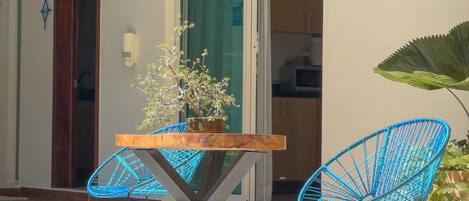 A poolside area with a table and chairs, a potted plant, and a sliding glass door leading to a kitchen.