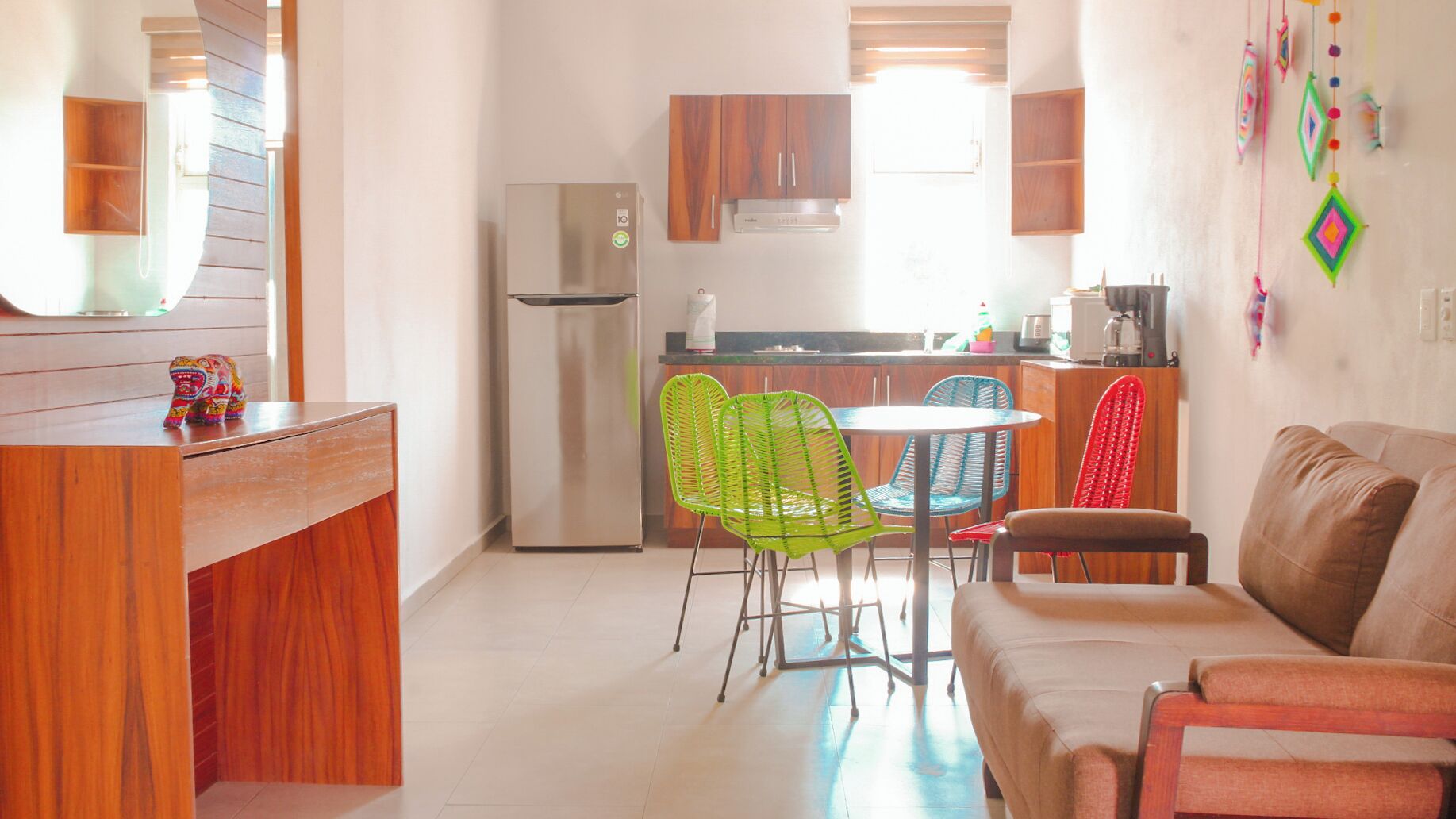 A compact living space with a kitchenette, a dining area with colorful chairs, and a sofa.