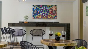 Un comedor moderno con una mesa de madera, sillas de estructura metálica negra y un cuadro abstracto colorido sobre la encimera.