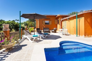 A pool area with lounge chairs, a table, and a large umbrella.