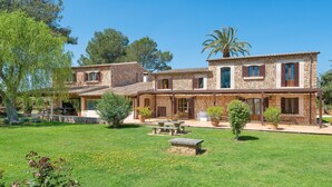 A stone house with a patio, outdoor seating, and a well-maintained lawn. - Luxurious villa in a rural idyll – Finca Can Duró (Binissalem)