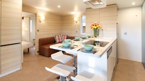 A modern kitchen with a central island, bar stools, a built-in oven, and a dining area with a sofa. - Nice apartment in villa for 4 people with A/C, WIFI, pool, TV, terrace and pets allowed (Ondres)