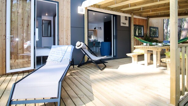 Eine Holzterrasse mit Liegestuhl, Hängematte und Essbereich mit Tisch und Stühlen.