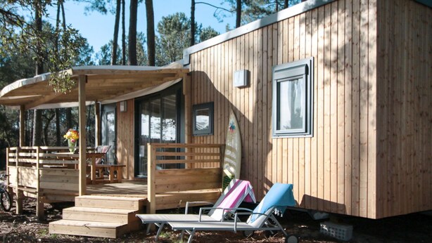 Een houten chalet met een veranda, een overdekte zithoek en een klein terras.