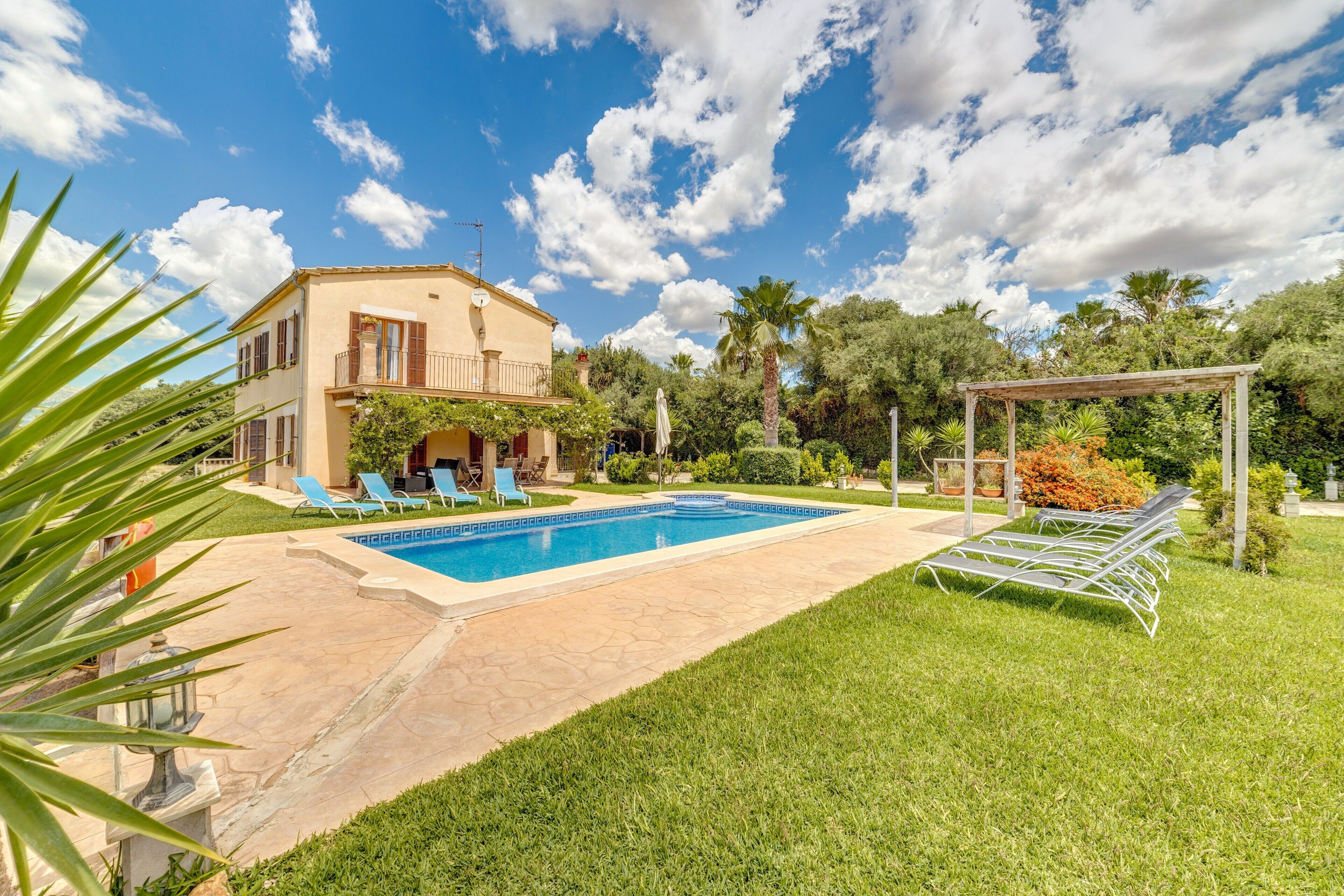 Una casa con piscina, pérgola y césped bien cuidado.
