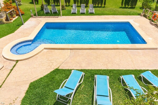 Una piscina rectangular con borde de azulejos, rodeada por un patio de piedra.