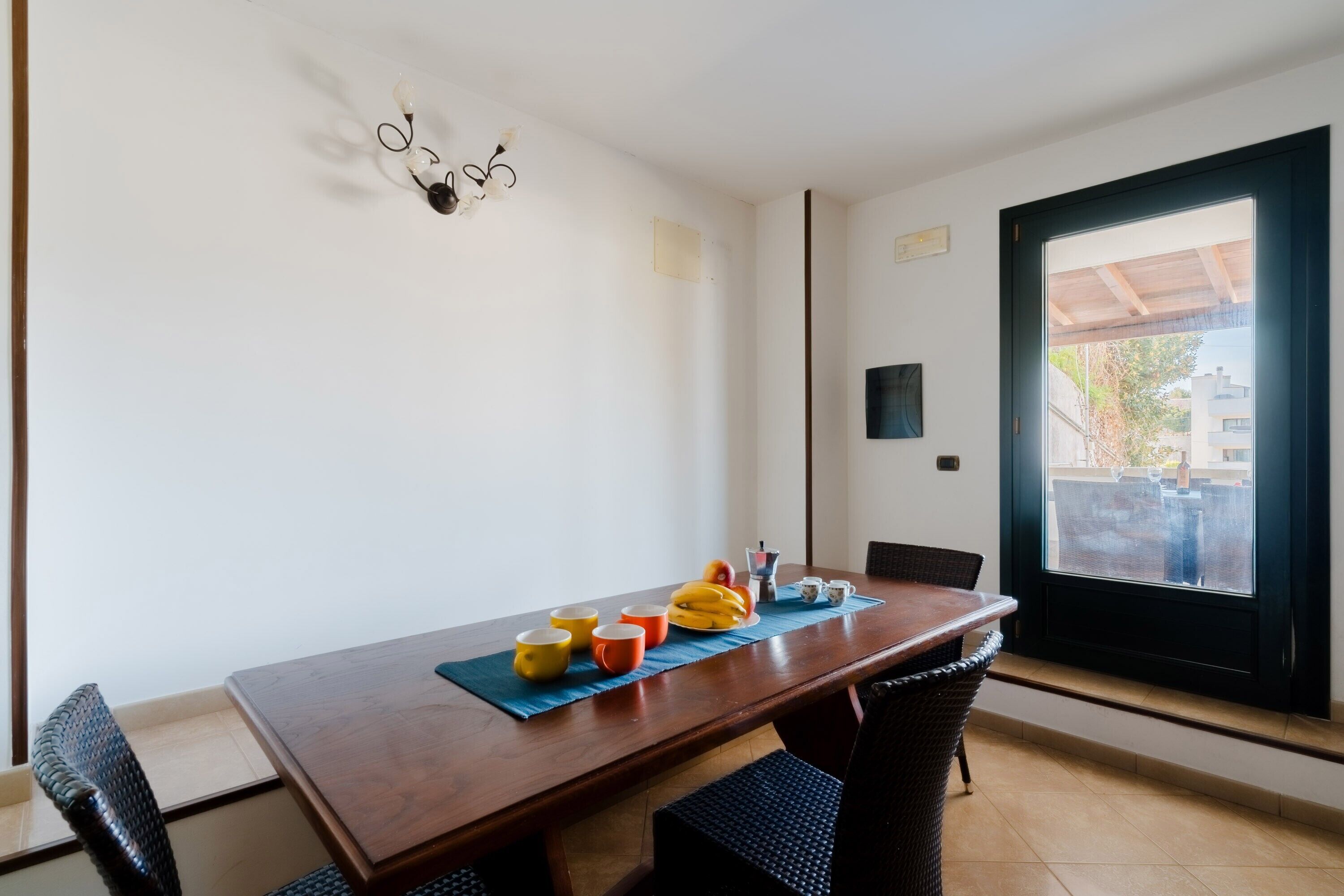 Un comedor con mesa de madera, sillas y una ventana que ofrece vistas a edificios.