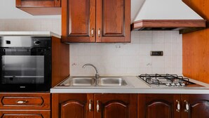 Une cuisine avec des meubles de rangement en bois, un évier à deux bacs, une cuisinière et un four.