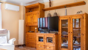 A living room with wooden cabinets, a flat-screen TV, a sofa, and a coffee table. - Holiday Home Casa Hermosa with Pool, Terrace, Air Conditioning and WiFi (Capdepera)