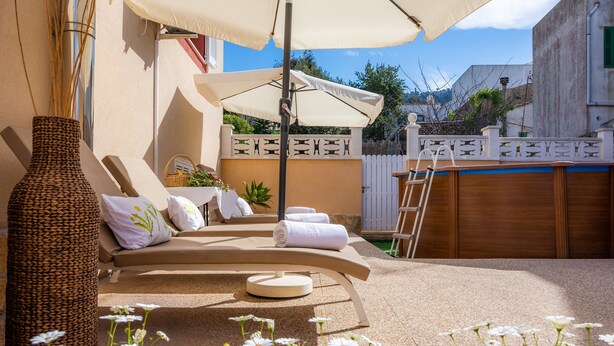 A sunlit outdoor lounge area with a beige sofa, a large umbrella, and a decorative vase. - Holiday Home Casa Hermosa with Pool, Terrace, Air Conditioning and WiFi (Capdepera)