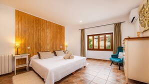 A bedroom with a bed, bedside tables, a chair, a window, and a wooden wall. - Holiday Home Casa Hermosa with Pool, Terrace, Air Conditioning and WiFi (Capdepera)