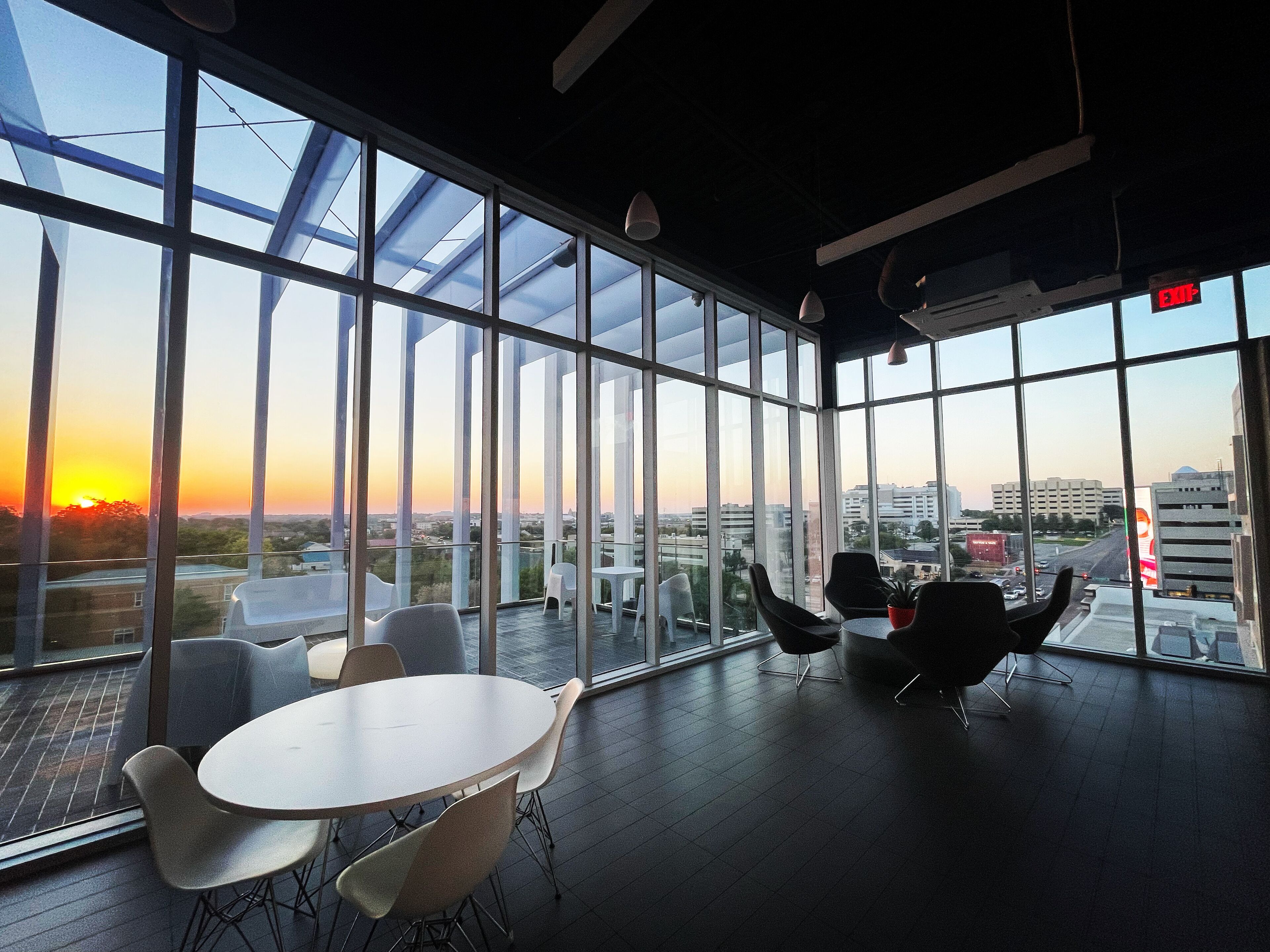 A modern interior with large windows, a round table, and several chairs.