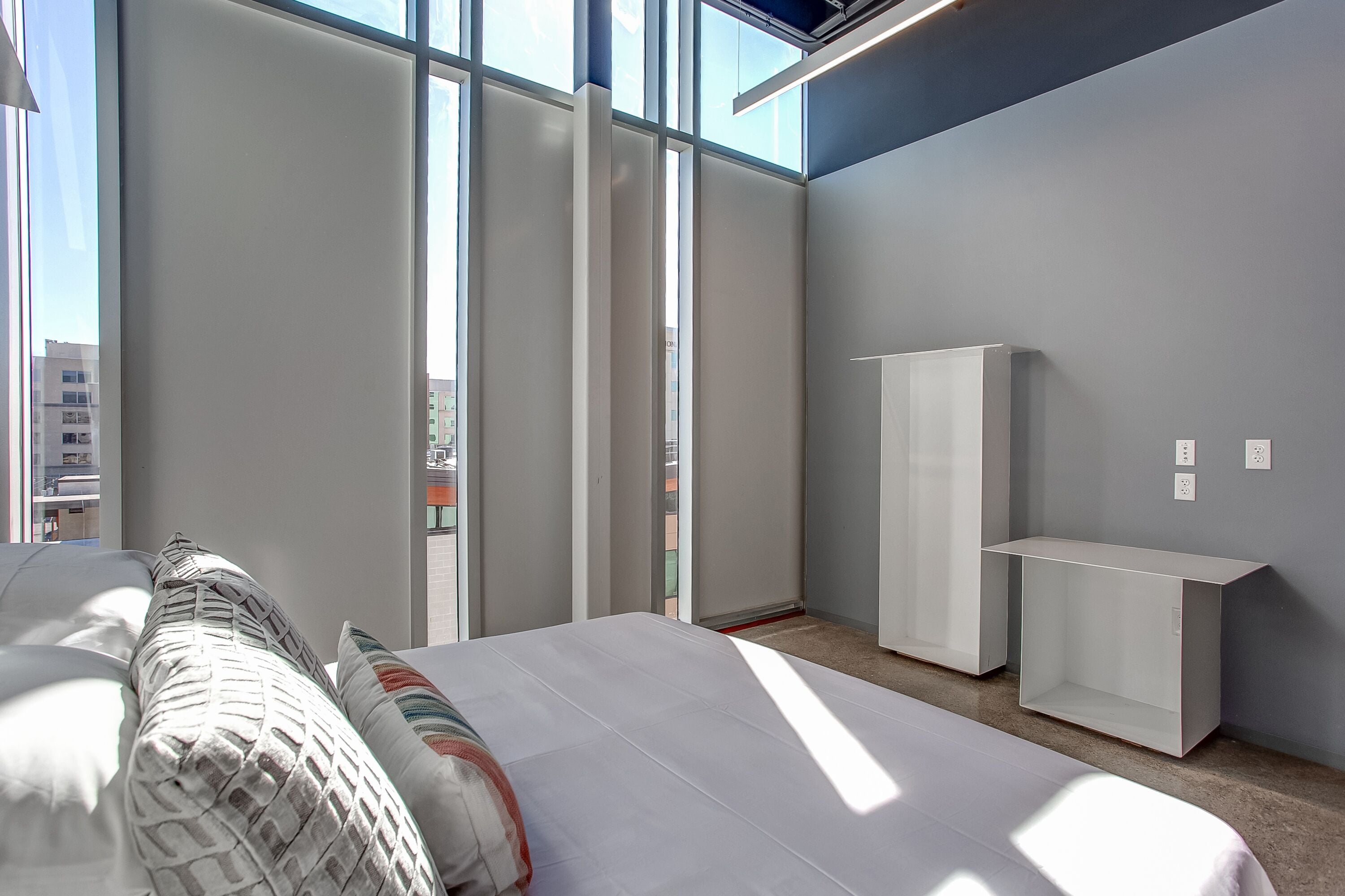 A modern hotel room with a large bed, a wardrobe, and a desk.