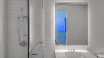 A modern bathroom with a glass shower enclosure, a white sink, and a large mirror.